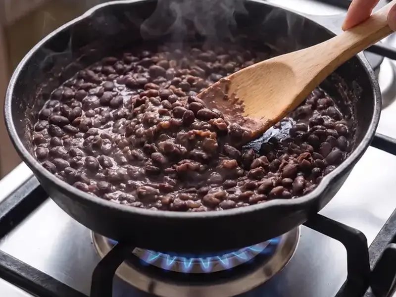 Ripieno dei tacos di fagioli neri: la spatola schiaccia una parte dei fagioli, gli altri restano interi.