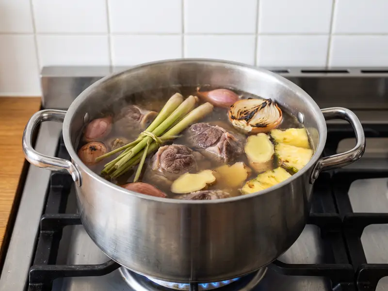Lemongrass bundles, charred aromatics and pineapple simmering with beef shank and ribs