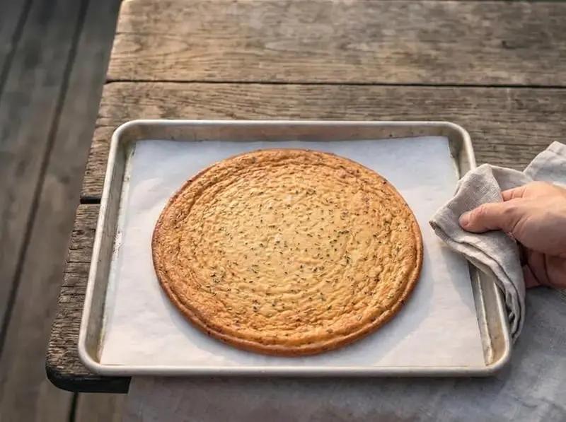 Piadina di fiocchi di latte appena sfornata su una teglia con carta forno, dorata in modo uniforme e asciutta ovunque