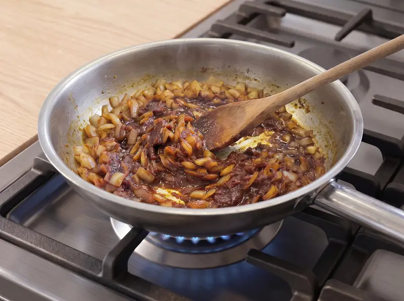 Le concentré de tomate, le paprika doux et le curry revenus avec l'oignon fondu jusqu'à ce que la pâte fonce