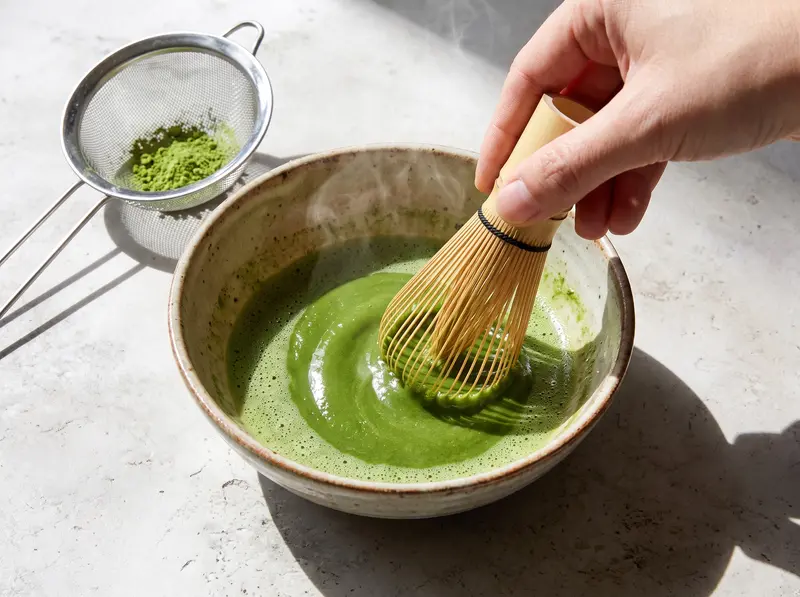 Iced matcha: bright green matcha whisked with a little hot water into a smooth glossy paste with a bamboo whisk