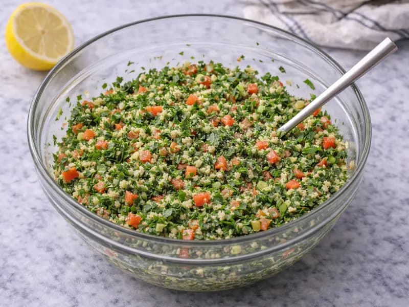 Angemachtes Taboulé in der Schüssel, kräutergrün mit Tomate und Bulgur