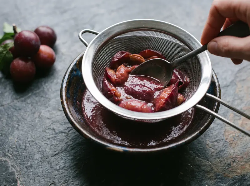 Cooked plums pressed through a sieve into smooth tkemali puree, pits left behind