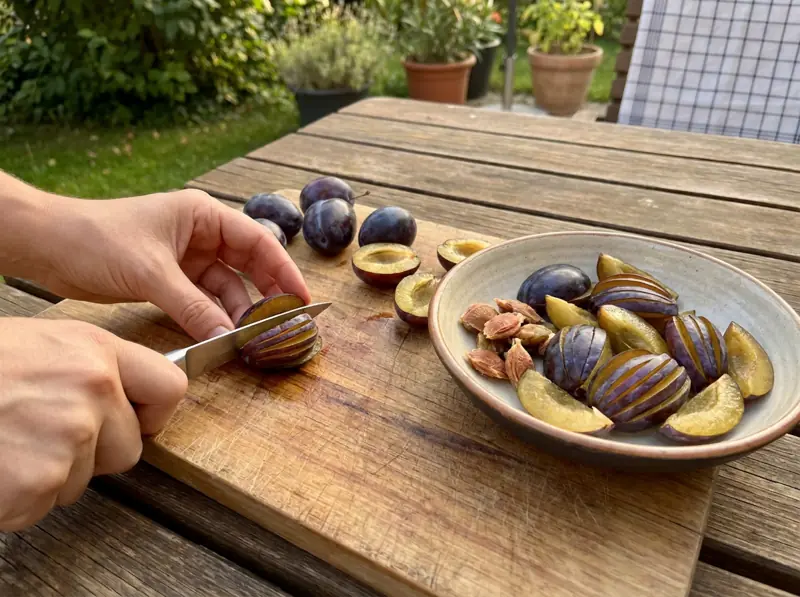 Halving Zwetschgen plums, removing the pits and scoring the halves into fans on a board